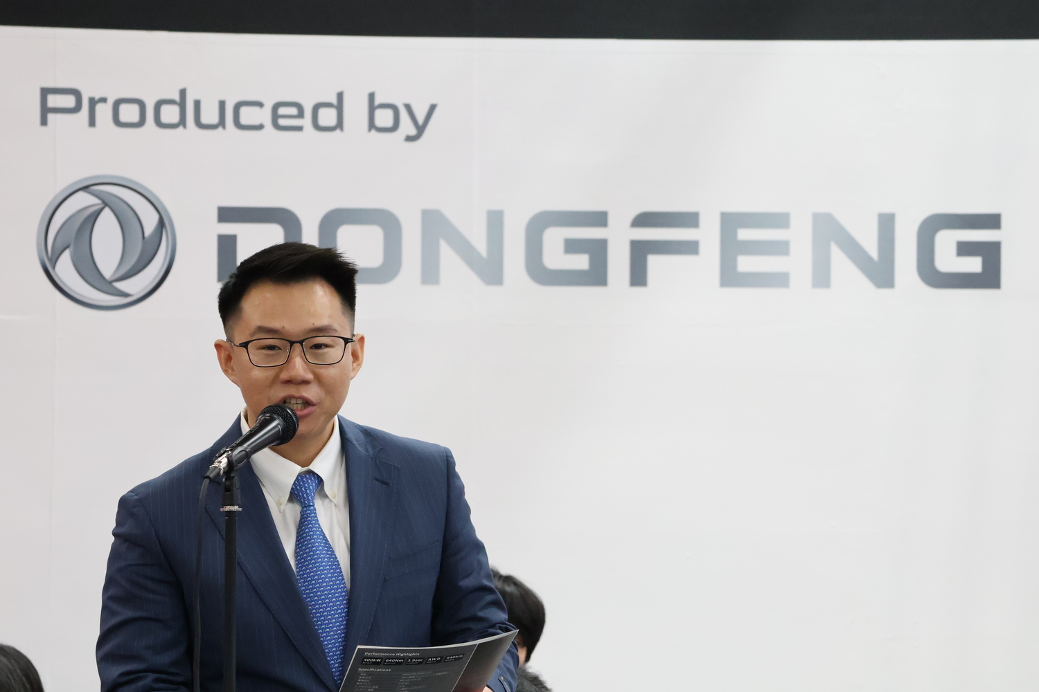 東京オートサロン2026でモンスタースポーツ007の発表を行うドンフェン・ジャパン執行役員のザック・リュウ氏